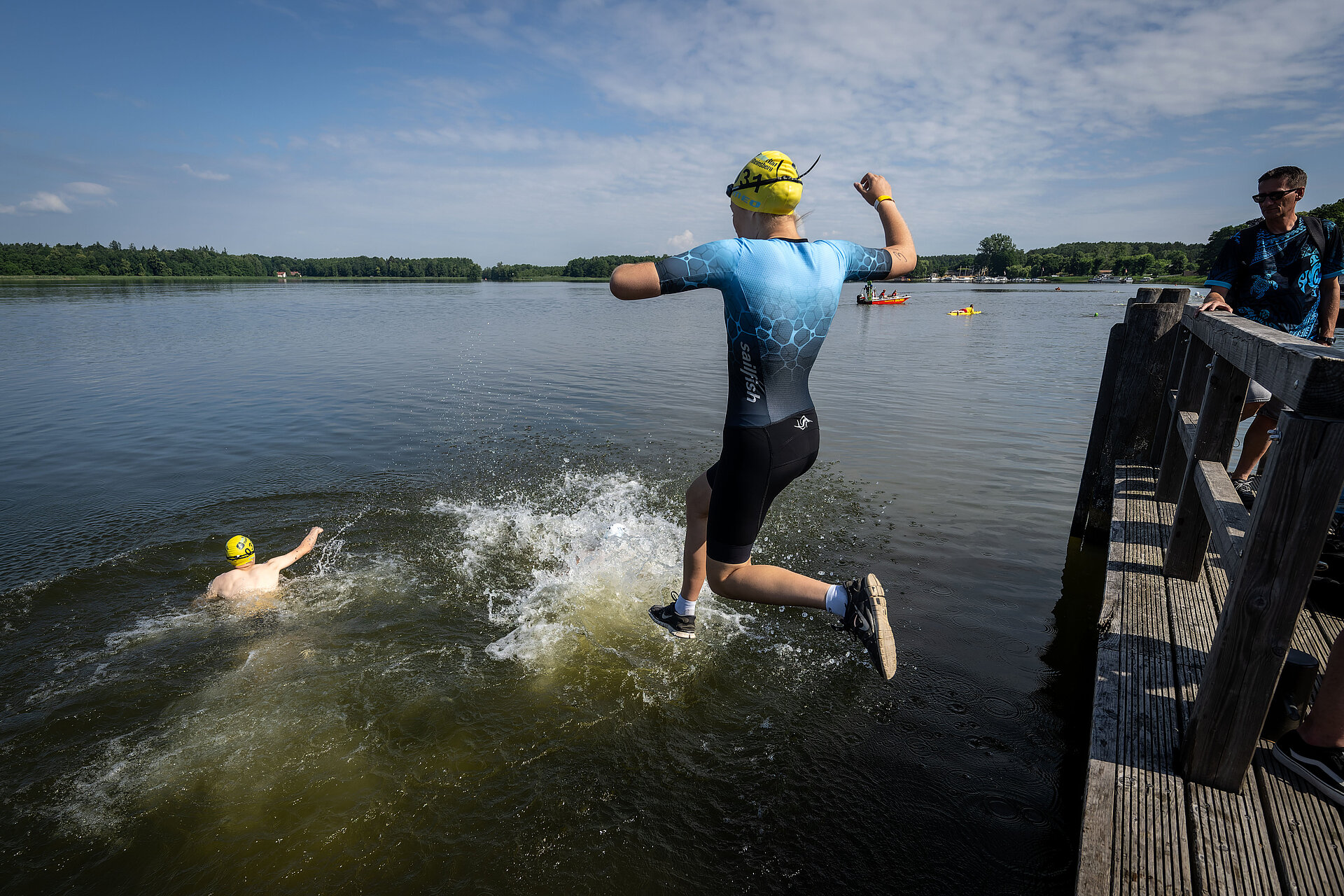 Teilnehmerin des SwimRun Rheinsberg beim Sprung ins Wasser, in dem bereits jemand schwimmt.