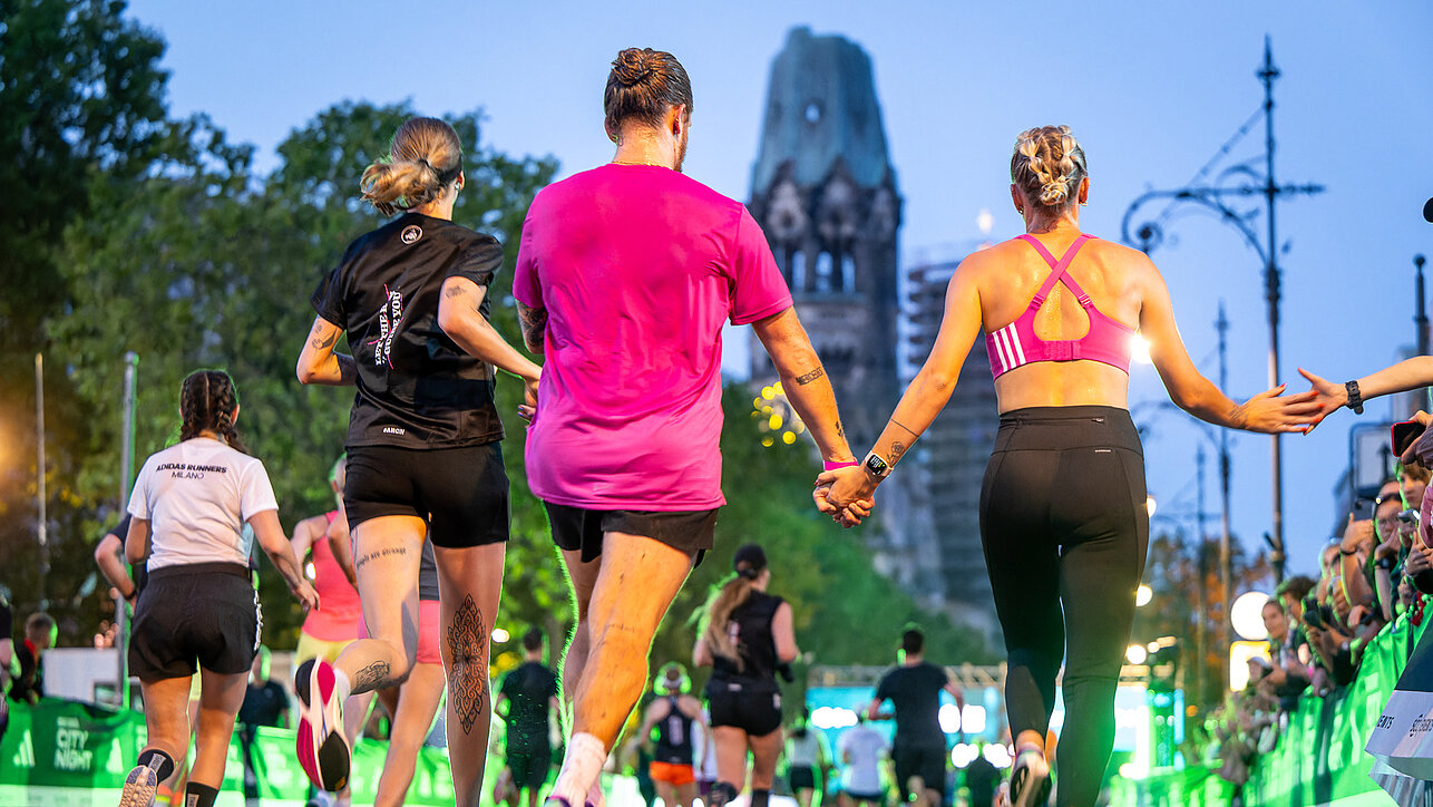Runners holding hands on the way to the finish with the memorial church in the background