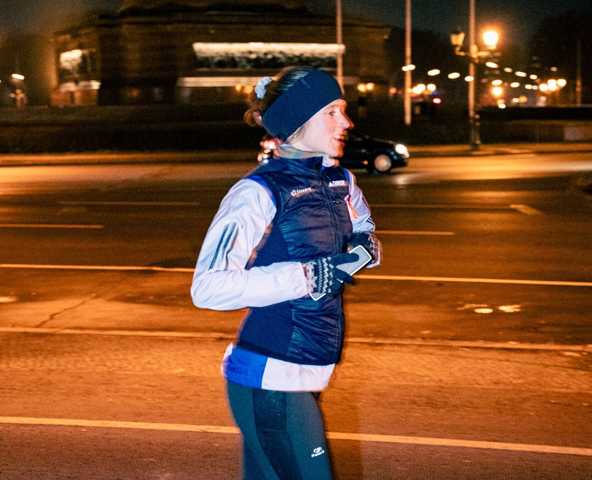 Frau in Winterkleidung joggt im Dunkeln.