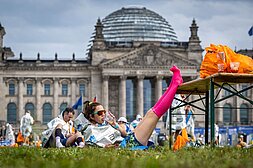 Finisherin des Marathons liegt vor dem Reichstag, trinkt etwas und hat ihre Beine hochgelegt.