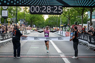 Hendrik Pfeiffer läuft über die Ziellinie der adidas Runners City Night 2025 und bricht den Streckenrekord