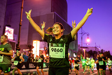 Runner on the track beaming and raising both hands