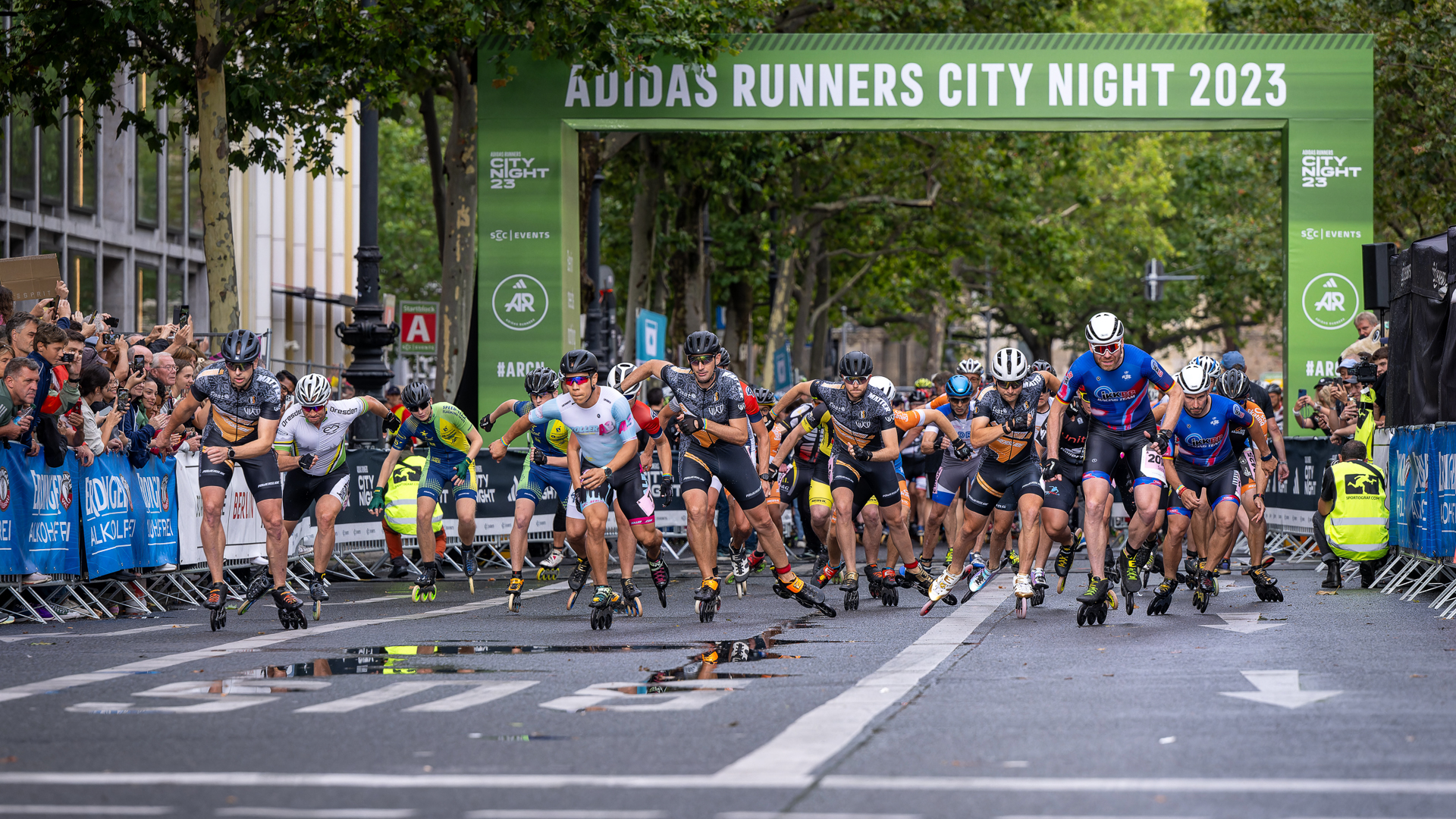 Skaters start their race with the start gate in the background.